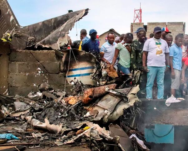 Rescuers and onlookers gather amidst the debris of an aircraft operated by private carrier Busy Bee which crashed in Goma, Congo Sunday, Nov. 24, 2019. (AP Photo/Justin Kabumba)